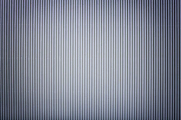 Texture of corrugated dark gray paper with vignette, macro. Striped pattern of silver cardboard background, closeup.