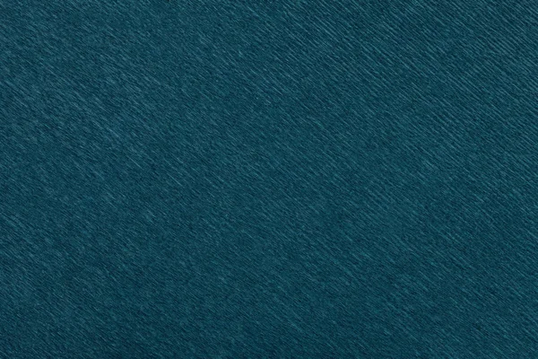 Textural of navy blue background of wavy corrugated paper, closeup. Structure of wrinkled crepe dark emerald cardboard macro.