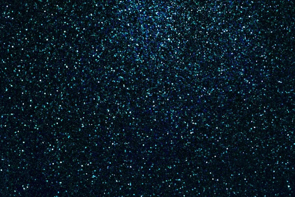 Navy blue sparkling background from small sequins, closeup. Brilliant turquoise shiny backdrop from textile. Shimmer denim paper