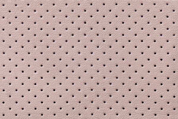 Perforated beige leather texture background, closeup. Light brown backdrop from wrinkle skin.