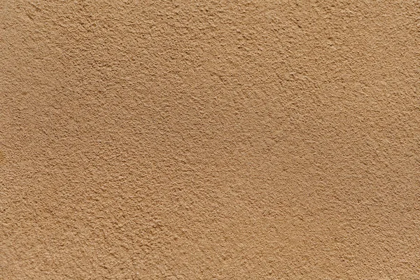 Alte helle Sandmauer mit schäbigem, unebenem Putz bedeckt. Textur der goldenen Steinoberfläche. — Stockfoto