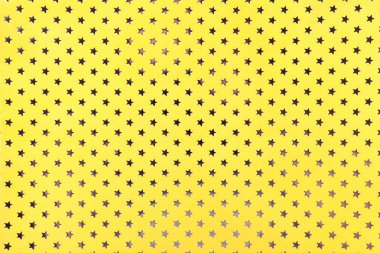 Altın yıldız desenli metal folyo kağıttan sarı arka plan