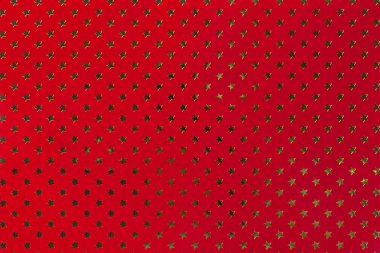 Altın yıldız desenli metal folyo kağıttan koyu kırmızı arka plan.