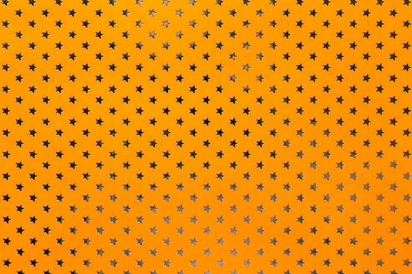 Orange background from metal foil paper with a golden stars pattern — Stock Photo, Image
