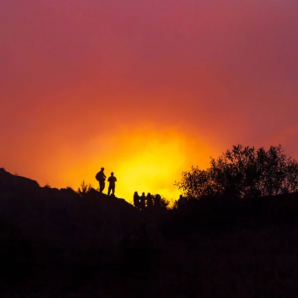 A group of people meet the sunrise at the peak of the mountain.