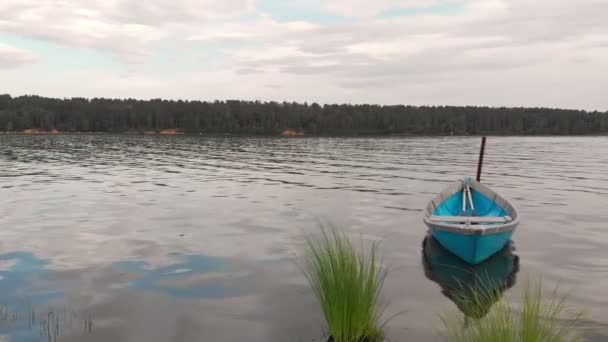 Gammal blå träbåt ankrad utanför kusten av viken gungor på lugna vågor. — Stockvideo
