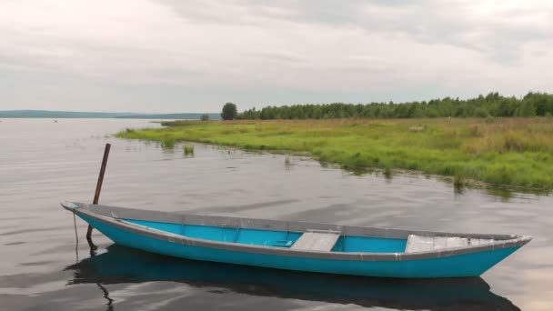 Antiguo barco de madera azul anclado frente a la costa de la bahía se balancea en olas tranquilas. — Vídeo de stock