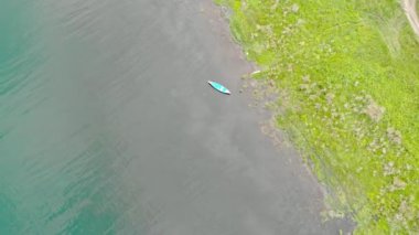 Eski mavi ahşap tekne sakin dalgalarda sallanıyor. Nehirde sakin bir sabah. Üst görünüm