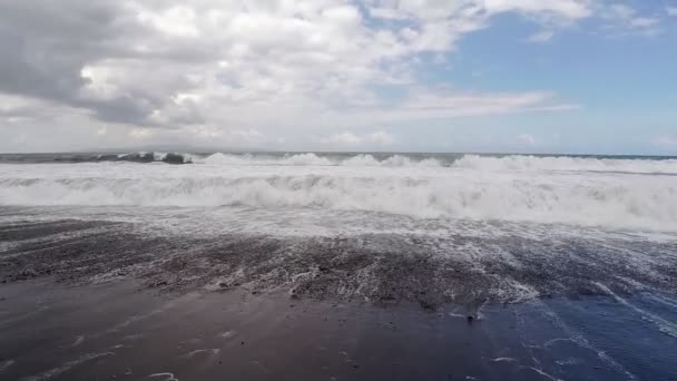 Grandes ondas oceânicas quebrando a costa da praia vulcânica negra. Vista em câmara lenta. — Vídeo de Stock