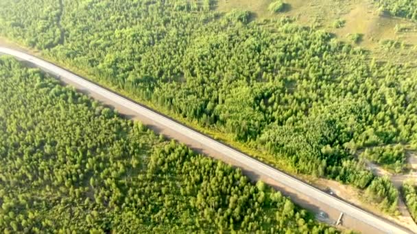 Lucht vliegen over een landelijke weg met twee auto 's tegenover elkaar op de baan tussen bos op een zonnige dag. — Stockvideo
