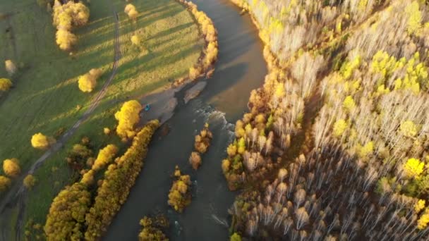 Luftaufnahme von der Drohne über einen kurvenreichen Fluss, kahlen Wald und eine Landstraße. — Stockvideo