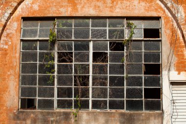 Old broken window glass on orange brick wall clipart