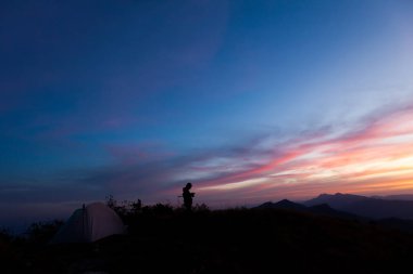 Tanınmayan insanlar dağ manzarasında cep telefonu kullanıyorlar.