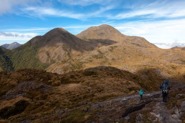Dağ manzarasında büyük sırt çantalarıyla yürüyen insanlar - Brezilya 'nın Mantiqueira aralığında dağ yürüyüşü yapıyorlar.