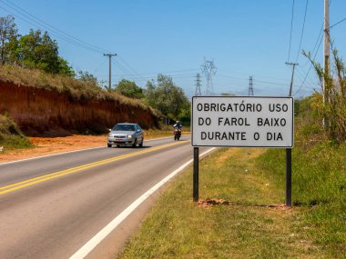 SAO PAULO, BRAZIL - 26 EYLÜL - Yeni bir trafik levhası ile yol gün içinde bile ışıkları açık bir araba ve motorsikletle yollarda bile farların kullanılmasını gerektiren yeni bir yasa