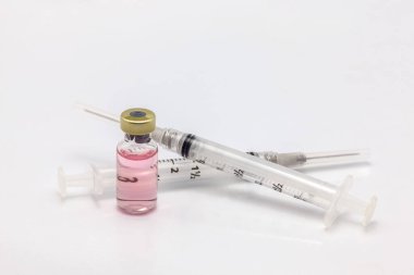 Renkli sıvıyla izole edilmiş cam aşı şişesi ve boş iki şırınga.