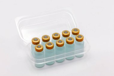 İçinde on aşı şişesi açılmış şeffaf plastik kutu.