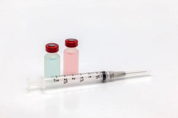 两个不同的分离塑料疫苗瓶 不同颜色的液体和一个空注射器 — 图库照片