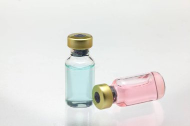 İki cam aşı şişesi izole edildi. Biri farklı renklerde, sıvıyla yatıyordu. Çok yakın büyütme modeli.