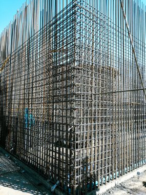 Bir sürü parmaklığı ve kablosu olan metal bir yapı. Parmaklıklar üçgen şeklinde. Yapısı tamamlanmamış ve o bir binanın parçası.