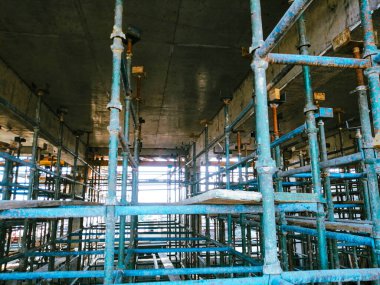 İnşaat iskelesi ve bir sürü mavi ve yeşil metali olan bir şantiye. Manzara endüstriyel ve muhtemelen kaotik.