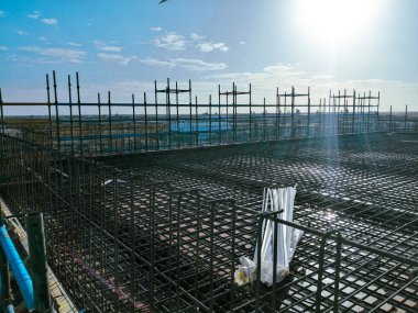 Büyük bir metal ağ alanı olan bir inşaat alanı. Örgü kahverengi ve gökyüzü mavi.