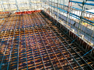 Büyük bir metal ağ alanı olan bir inşaat alanı. Örgü kahverengi ve gökyüzü mavi.