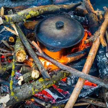 Kamp ateşinde yemek pişirmek.