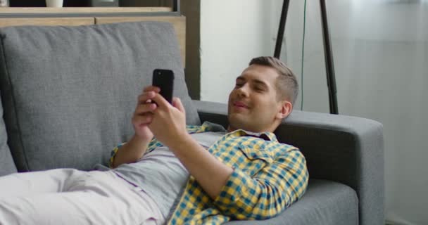 Jeune homme se relaxe avec son smartphone — Video