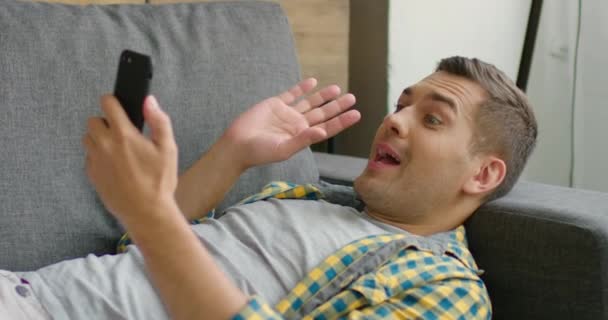 Junger Mann äußert sich im Gespräch per Smartphone überrascht — Stockvideo