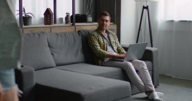 Kız yaklaşıyor ve gri bir kanepede erkek arkadaşı yakın oturur