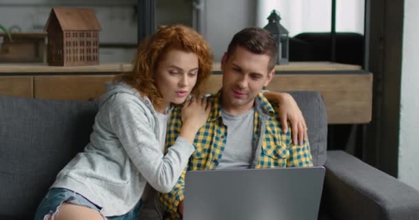 Молодой человек и женщина смотрят видео на своем ноутбуке — стоковое видео