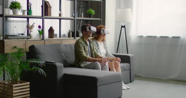 Mann und Frau sind beeindruckt, als sie zum ersten Mal virtuelles Reality-Headset ausprobieren — Stockvideo