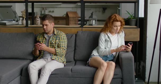 Les jeunes hommes et les jeunes femmes sont assis sur le canapé en utilisant leurs smartphones — Video