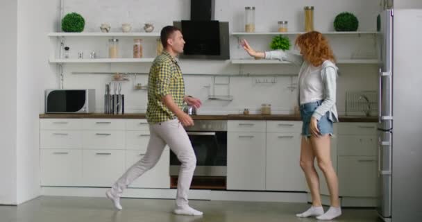 Mladý pár, muž a žena, tančí v nové kuchyni — Stock video