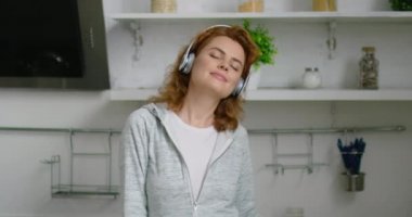 Kablosuz kulaklıkta genç kadın evde dans ediyor