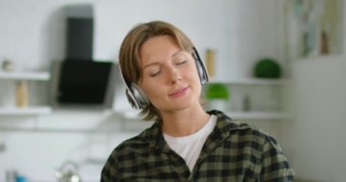 Kadın mutfakta kablosuz kulaklık müzik dinliyor