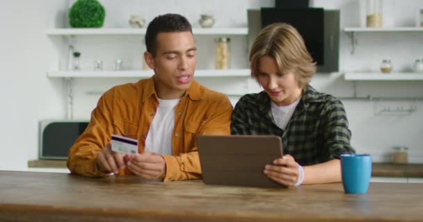 Молодая пара делает онлайн покупки на кухне — стоковое видео