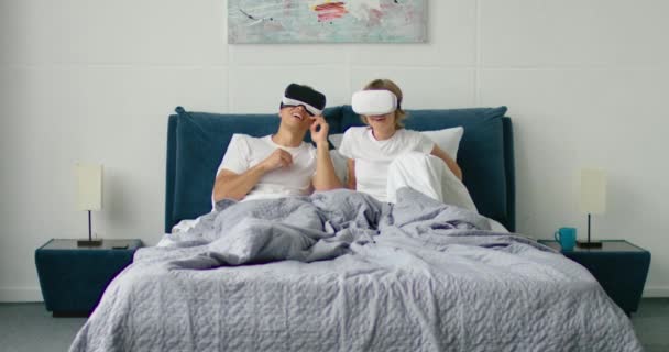 Jeune couple couché au lit, mettre des casques de réalité virtuelle sur — Video