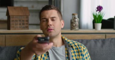 Genç adam kanepede oturuyor, Televizyonu açarak.