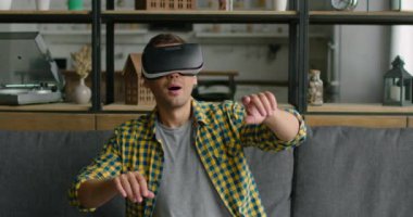 Sanal gerçeklik kulaklığı takan, görüntüleri kontrol etmek için jestler kullanan genç adam