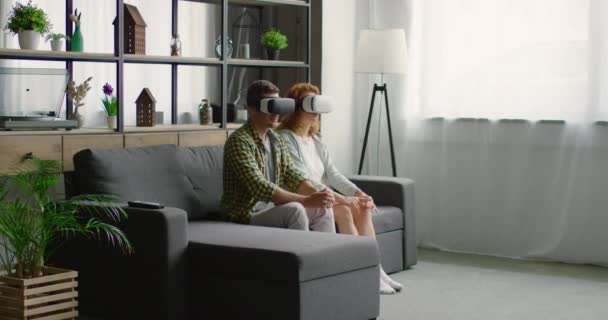 Pareja joven probando auriculares de realidad virtual en casa — Vídeos de Stock