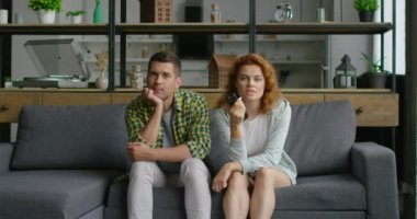 Genç çift oturma odasında Tv izliyor