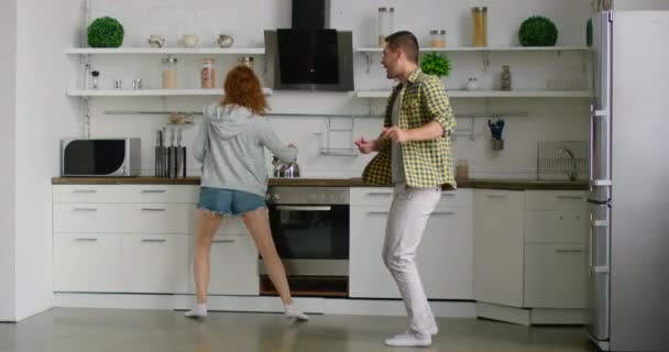 Joven pareja alegre es bailar y divertirse en la cocina — Vídeos de Stock