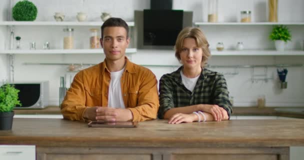 Retrato de una joven pareja mixta sentada a la mesa en la cocina — Vídeos de Stock