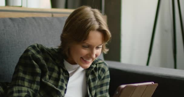女性は、タブレットコンピュータ上のビデオチャットを持っています, ソファに横たわって, クローズアップ — ストック動画