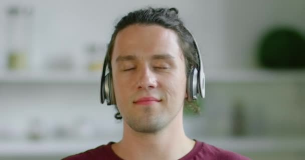 Jonge man neemt zijn draadloze hoofdtelefoon, onscherpe achtergrond — Stockvideo