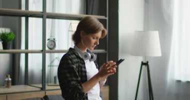 Genç kadın müzik dinlemek için gadget kullanarak, kablosuz kulaklık takıyor