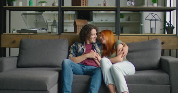 Νεαρό ζευγάρι στην αγάπη είναι χαλαρωτικό στον καναπέ στο σπίτι, απολαμβάνοντας τις σχέσεις τους — Αρχείο Βίντεο