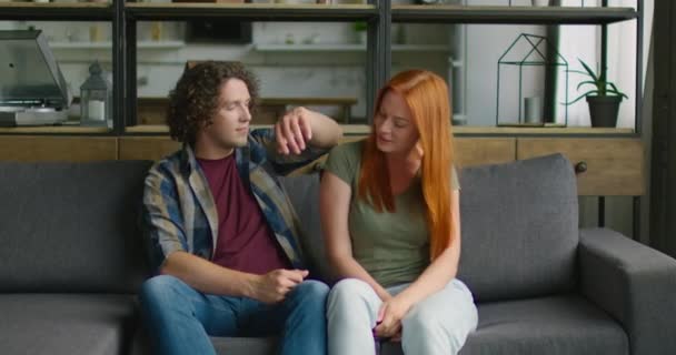 Молодая пара в романтическом настроении проводит время на диване в гостиной — стоковое видео